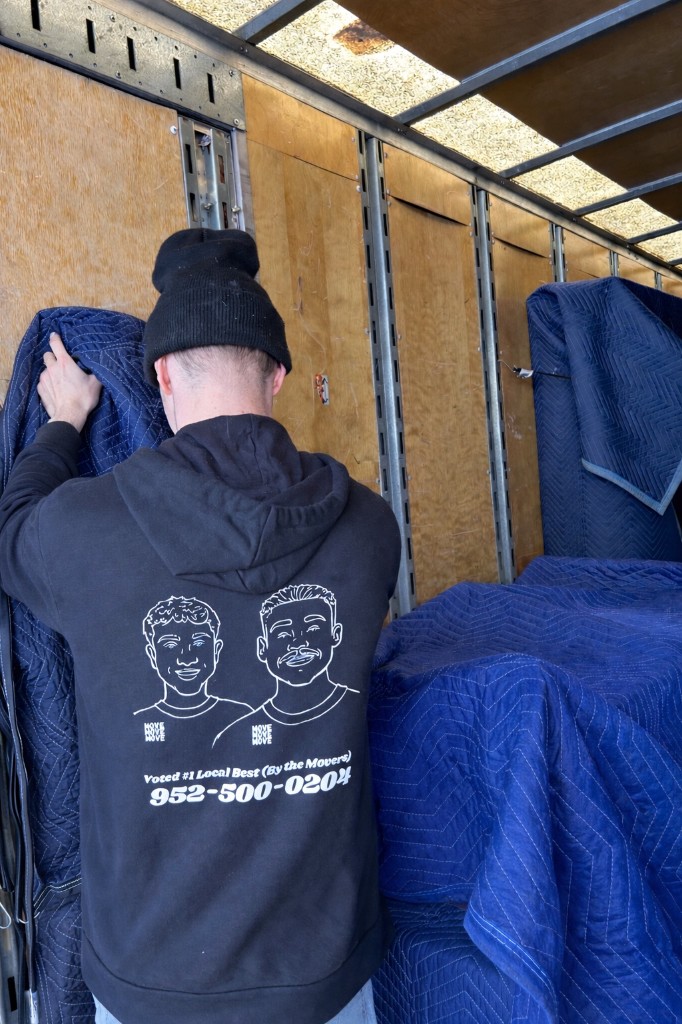 A mover in a MOVE MOVE MOVE hoodie inside the truck with quilted moving blankets