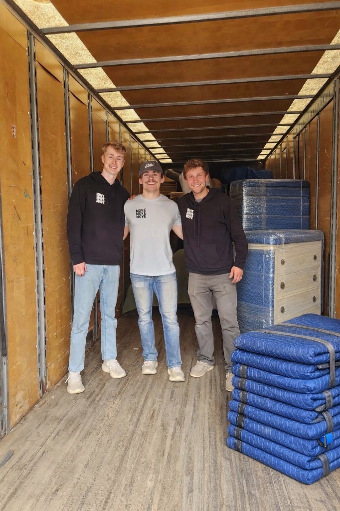 Three Move Move Move movers in the back of the truck with furniture wrapped in blankets