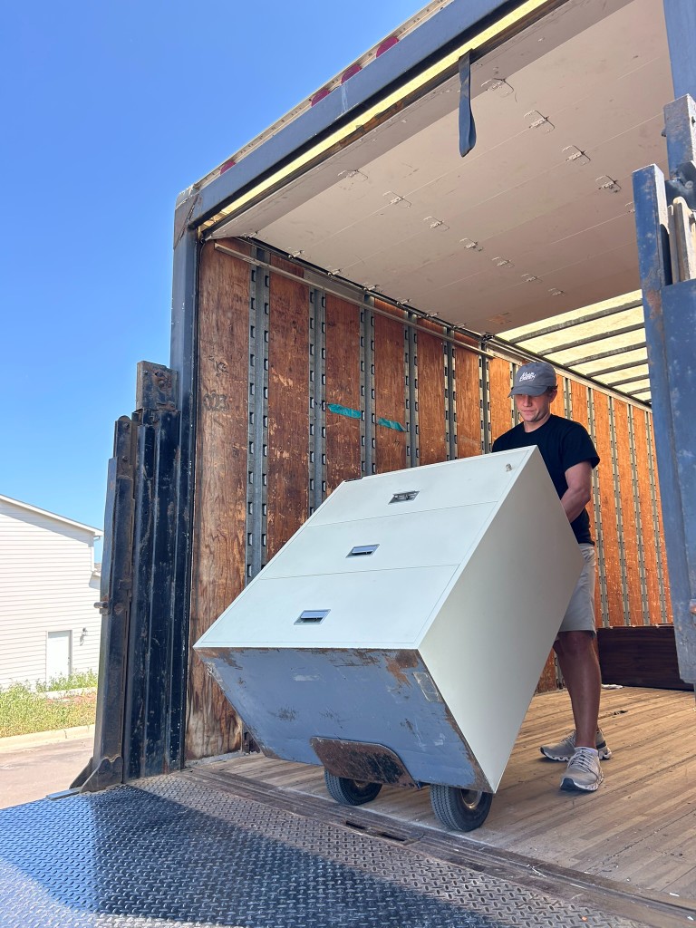 A Move Move Move mover loading a filing cabinet onto a dolly at the truck ramp