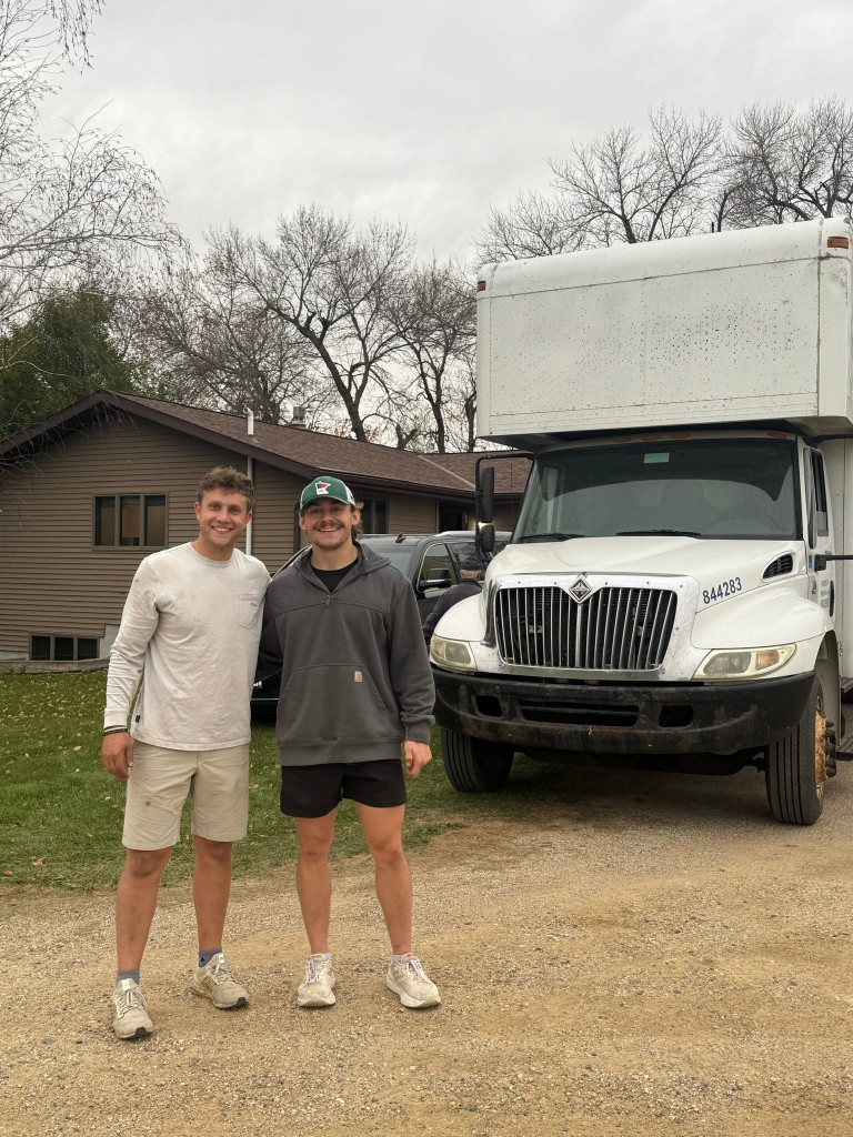 Two movers standing in front of the moving truck
